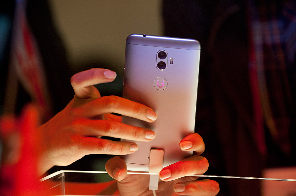 2月27日,在西班牙巴塞罗那,一名与会者在世界移动通信大会上试用中国手机品牌金立的A1手机。